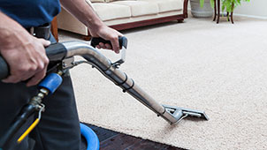 Professional steam cleaning of a beige nylon carpet in a residential home.