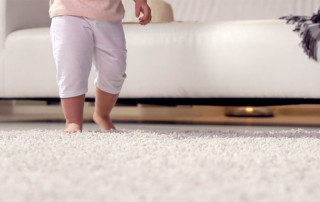 baby walking across white soft carpet at home